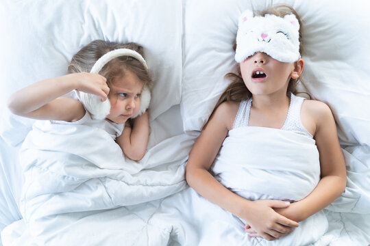 Little Girls Sleep In Bed. One Is Snoring Hard,sister Is Plugging Ears With Fur Headphones.Early Morning Wake Up,rise To Kindergarten,school. Bedtime,sweet Dreams.Kids Correct Daily Routine For Child