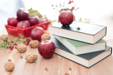 Red apples, walnuts and hawthorn berries. Autumn fruits and vegetables. Enjoy your time with books.
