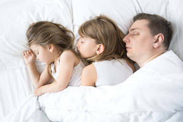 Kids, dad sleep together in bed on pillows under blanket. Family joint sleeping. Father with cute little daughters. Insomnia, night bedtime.Sweet dreams. arly wake up,rise to kindergarten,school,work