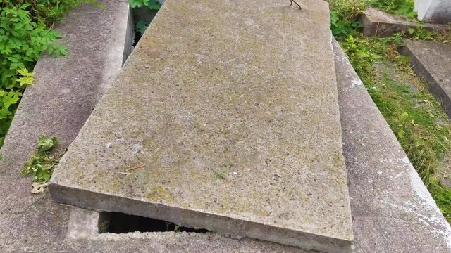 open new empty grave , cemetery. green moss on stone cover.