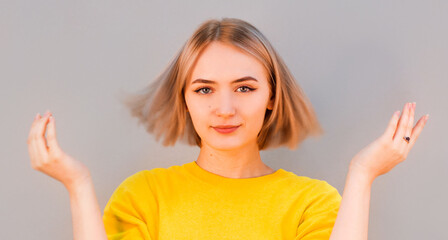 Fototapeta premium Awesome attractive joyful happy sexy female model is shaking head with blond hair in studio isolated on gray background