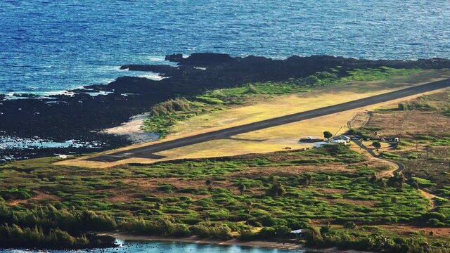 High angle establishing shot of Kalaupapa airport and small plane landing on the island of Molokai, Hawaii.