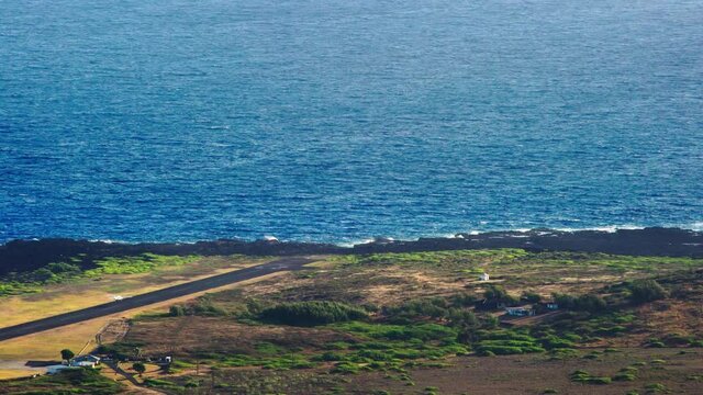 High angle establishing shot of Kalaupapa airport and small plane landing on the island of Molokai, Hawaii.