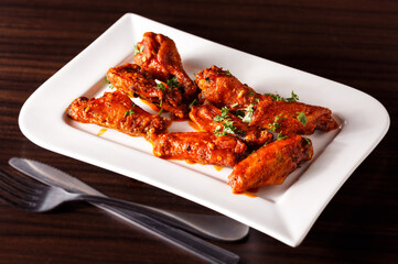 Spicy Chicken Wings in a White Plate on a Dark Surface