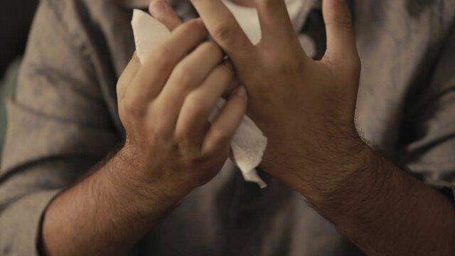 Man wipes her hands with a wet napkin