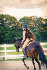 Girl riding horse in arena during late afternoon.