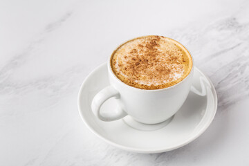 Coffee with milk, cappuccino in white cup on marble background, space for text, horizontal format