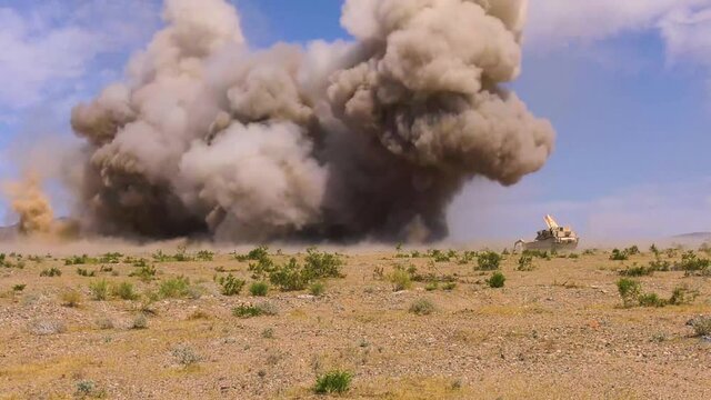 A huge explosion goes off in front of a M1150 Assault Breacher Vehicle thats sweeping a battlefield for mines, 2019