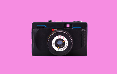 Front view of old stylish camera. Vintage 35mm film camera isolated on pink background
