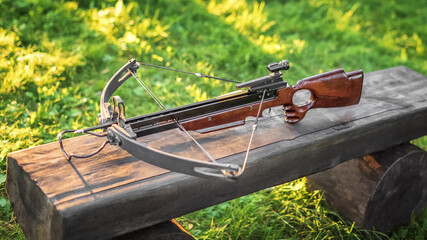 Loaded crossbow on a wooden bench. Selective focus. - obrazy, fototapety, plakaty