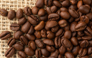 Closeup, top view of coffee beans over rustic bag