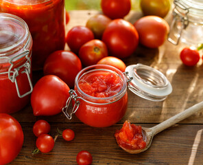 Homemade tomato preserves and fresh tomatoes  on a wooden table close up view