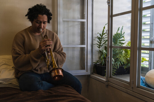 Young Man Playing Trumpet At Home