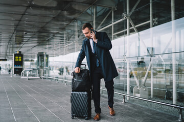 Caucasian businessman waiting near airport terminal using mobile phone for making international...
