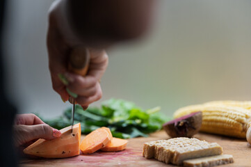 Low angle view of a woman cutting sweet potato on a cutting board