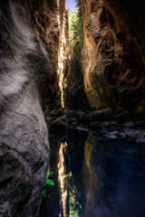 sunlight from above illuminating the white texured rocks in the Avakas gorge canyon in cyprus and reflecting in the running water below
