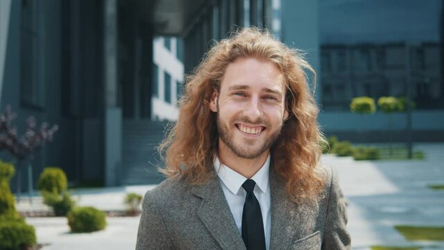 Outdoor potrait of attractive modern employee in smart-casual style clothes looking satisfied with broad cheerful smile. Business person. Caucasian young businessman.