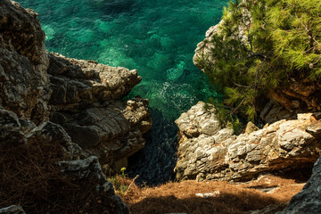 Rocky cliffs with pure clean green and blue water of Adriatic sea near Sveti Stefan island. Scary view from top.
