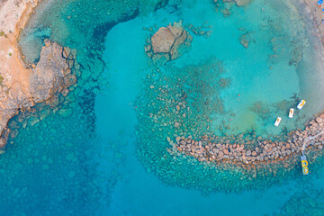 An aerial view of the beautiful Mediterranean Sea, where you can see the cracked rocky textured underwater corals and the clean turquoise water of Protaras, Cyprus,