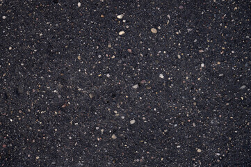 Abstract background of black wet asphalt with inclusions of pebbles