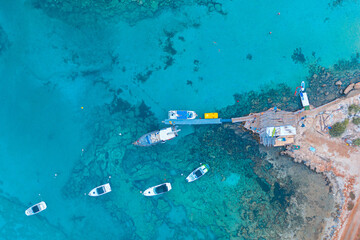 Aerial shot of boats on a crystal clear sea surrounded by rocks in Protaras, Cyprus	