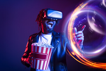 Man with VR glasses and popcorn watches a 3D film - obrazy, fototapety, plakaty
