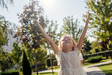 Fototapeta na wymiar little girl in a white dress on sunshine