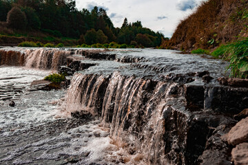 A stone in the middle of a river or a lake. A bunch of rocks in the running water. The river, the waves, the current.