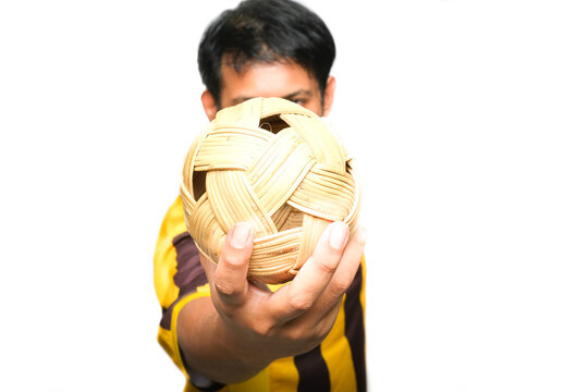 Selective focus of "takraw" been hold by a men on isolated white background. "Sepak takraw" or kick volleyball is a sport native to Southeast Asia.