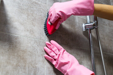 Woman hands in pink rubber gloves cleaning washing sink in bathroom. Close up. Disinfection of bath.