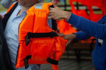 Puts on a life jacket. A man prepares to swim on the lake. 