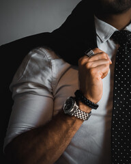 businessman adjusting his tie and wearing rings, watch and a leather bracelet