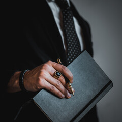 businessman holding a notebook and wearing ring and bracelets