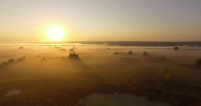 Aerial view of yellow sunrise on misty valley of Siverskyi Donets river near Zmiiv city, Ukraine. Vertical camera movement