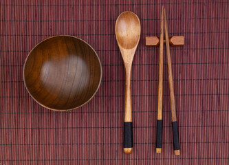 Wooden spoon, chopsticks and bowl on bamboo place mat 