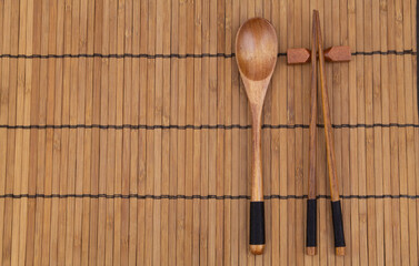 Wooden chopsticks and spoon on bamboo place mat  with copy space