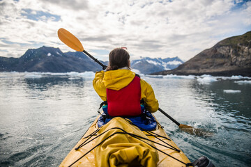 Woman paddle a canoe on an icy bay in Alaska exploring glaciers