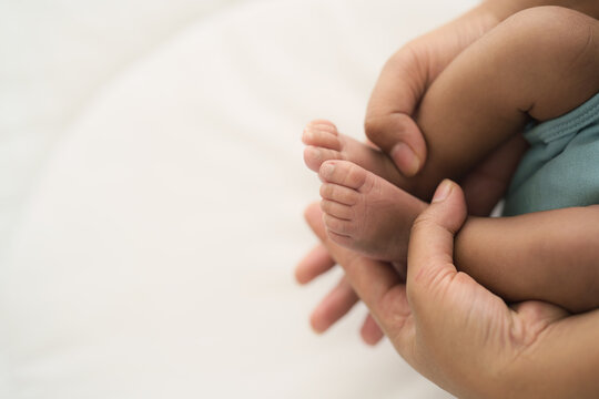hands of mother grabbing infant baby feet while holding