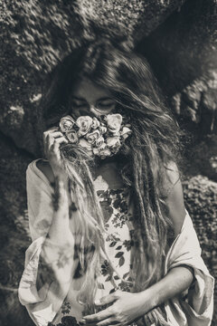 beautiful young woman cover her face with flowers. black and white portrait. conceptual tilt shift effect.