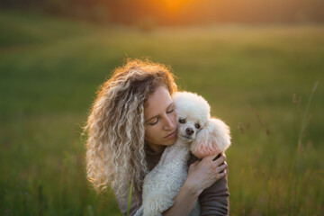nice woman and dog on a field at sunset. Walking with pet in nature