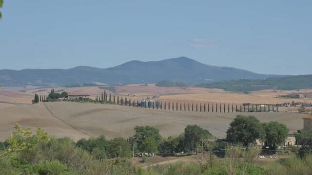Bagno Vignoni, Tuscany, Italy. August 2020. The amazing Tuscan countryside: the footage highlights the cypress-lined avenue of a farmhouse on top of a hill. Pan movement.
