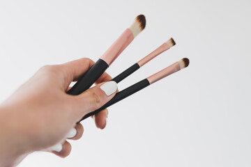 hand holding make-up brushes in front of the camera showing the product shot at shallow depth of field