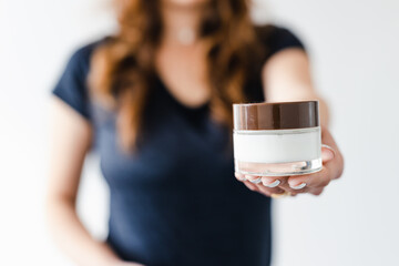girl holding moisturizer jar in front of the camera showing the product, beauty bloggers and...