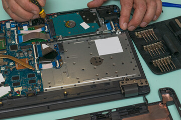 A man is replacing a hard drive on a laptop.