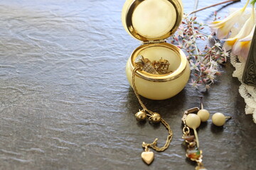 Gold Jewellery. Bracelet, wedding rings, earrings, gold chain, heart pendant, alabaster box in a dark background.
