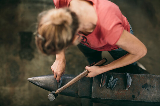 Young woman using hammer and anvil