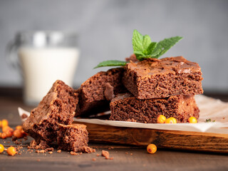 Brownie cookies lie on the board, in the background a glass with milk.