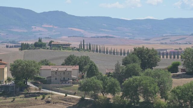 Bagno Vignoni, Tuscany, Italy. August 2020. The amazing Tuscan countryside: the footage highlights the cypress-lined avenue of a farmhouse on top of a hill.