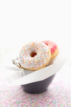 Colourful doughnuts with sugary on them pile in a cup on flowered cotton cloth