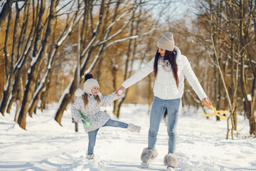 Fototapeta na wymiar young and stylish mom with long dark hair playing with her little cute daughter in winter snow park